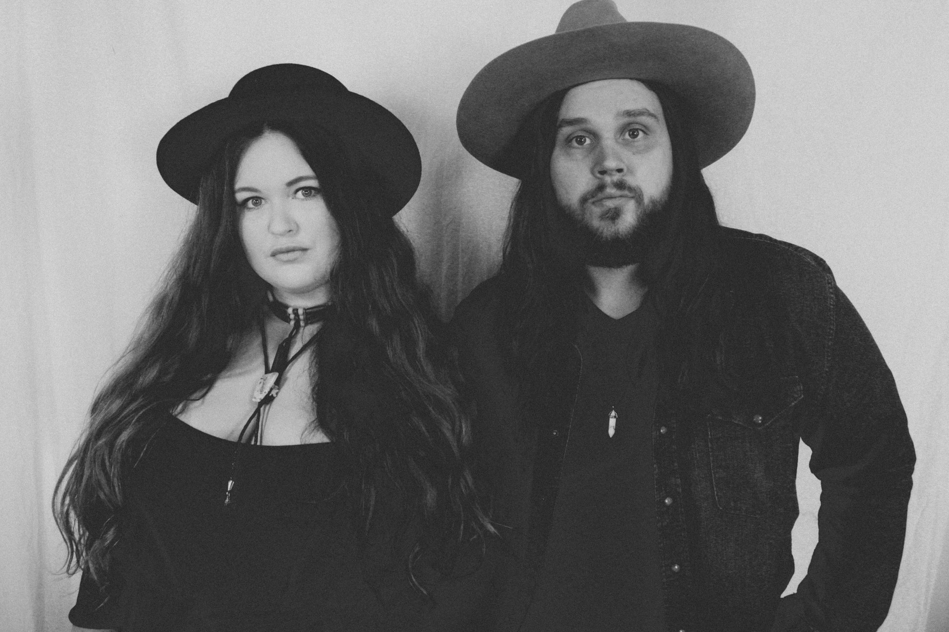 Man and a woman wearing hats posing for a photo.