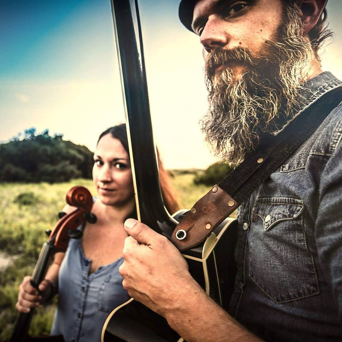 Couple holding instruments smiling at the camera.