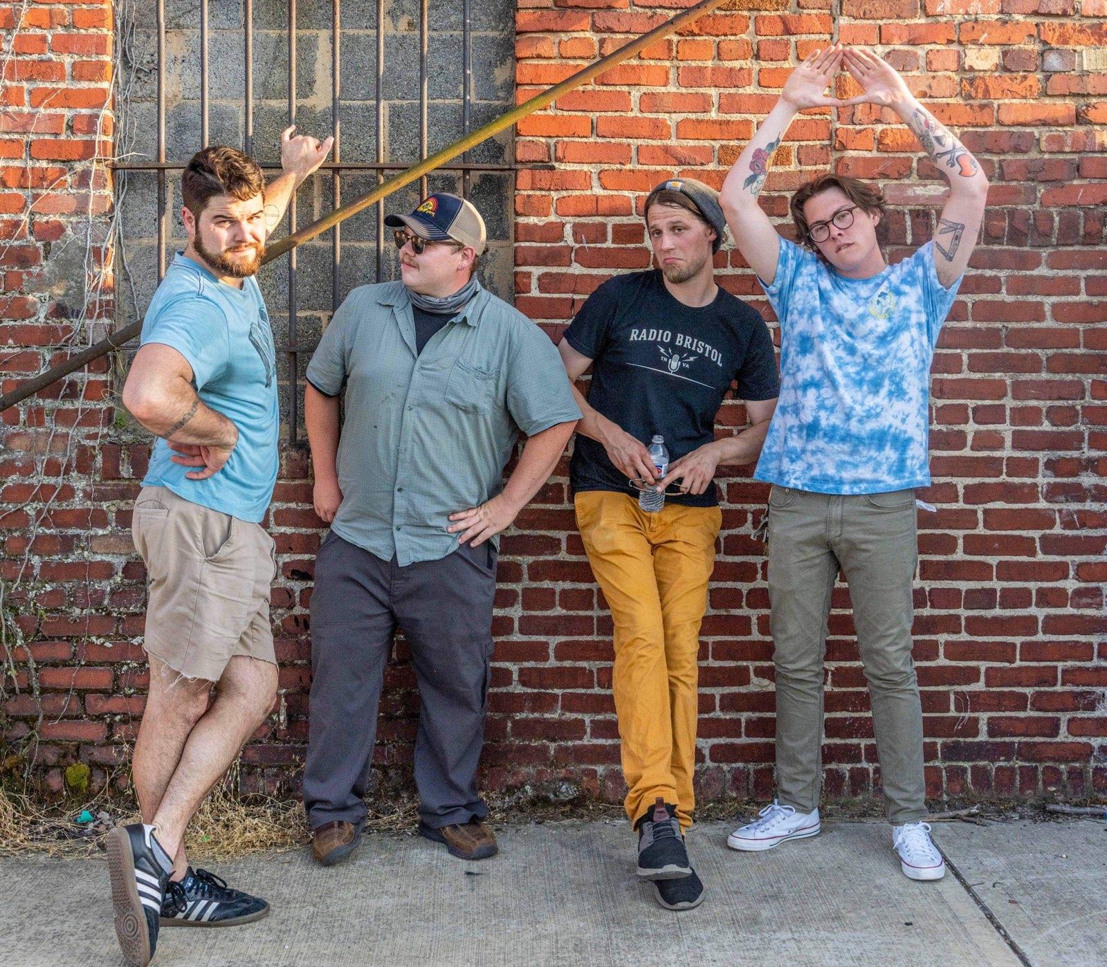 Donnie & the Dry Heavers stand against a brink wall posing in a line.