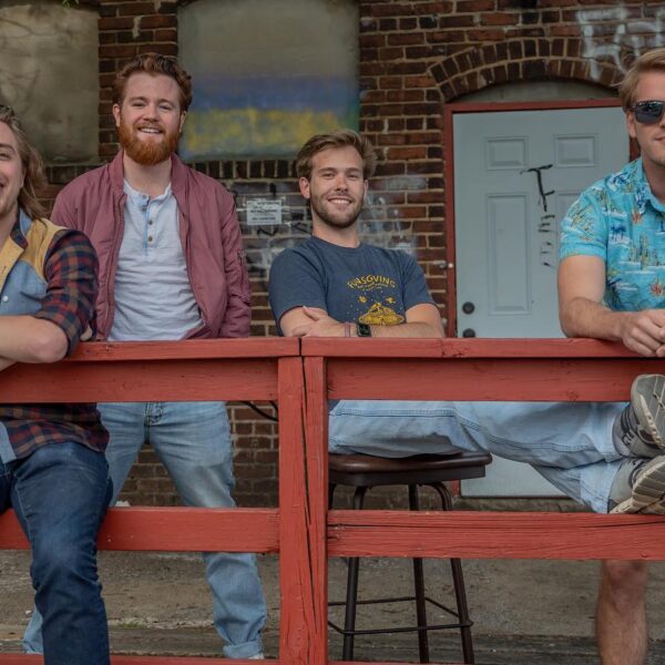 Four members of The Talisman pose for the photo in front of a red railing