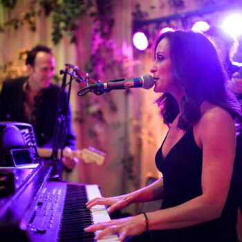 Pianist plays piano and sings in bar as patrons watch